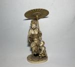JAPON
Okimono en ivoire sculpté représentant une femme à l'ombrelle aurpès...