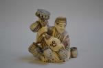 CHINE
Sujet en ivoire représentant un personnage assis tenant des paniers...
